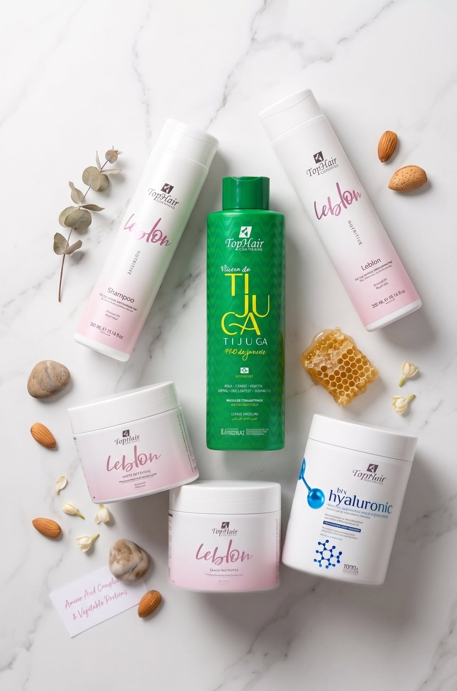 A flat-lay arrangement of Barra da Tijuca haircare products on a white marble background, including a Leblon shampoo bottle, a pink and white conditioner bottle and several white jars with pink and blue labels.